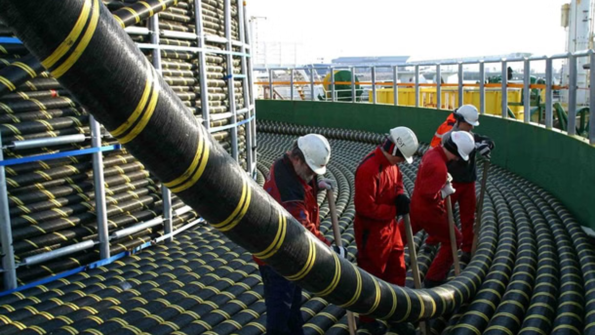 Engineers handling large subsea communication cables on installation site