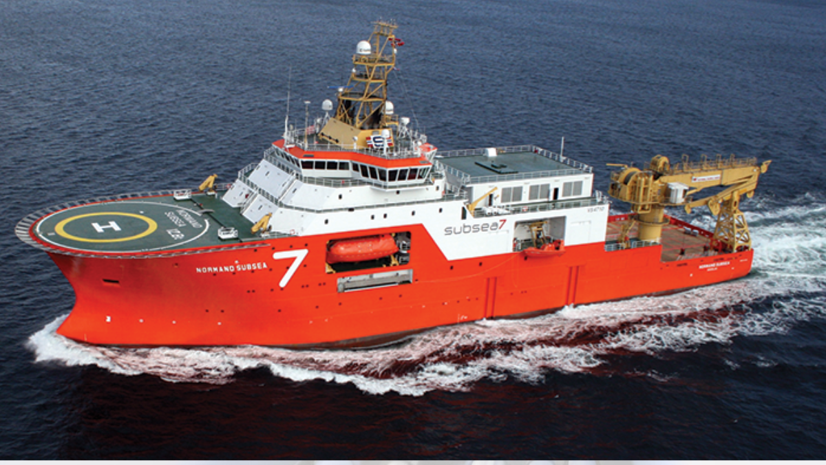 Bright red subsea engineering ship cruising through deep ocean waters.